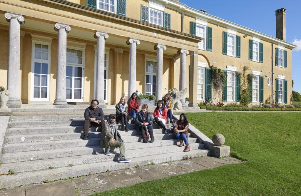 ITP fellows sitting on the steps outside of a country house