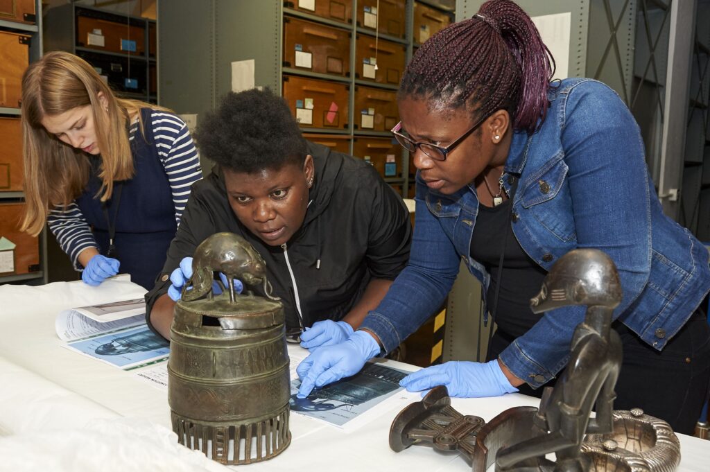 ITP participants wearing gloves examine a metal museum object.