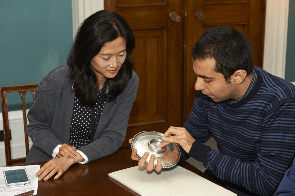 Two people sit and examine a museum object