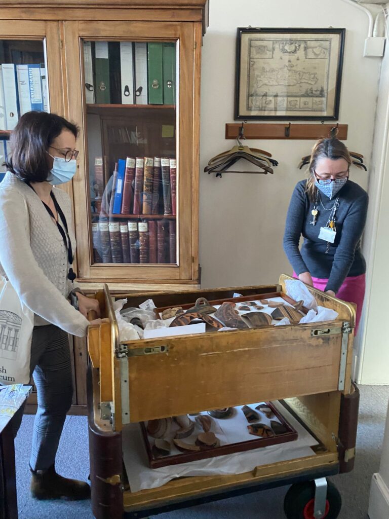 Two people look into a wooden trolley carrying ceramic museum objects.