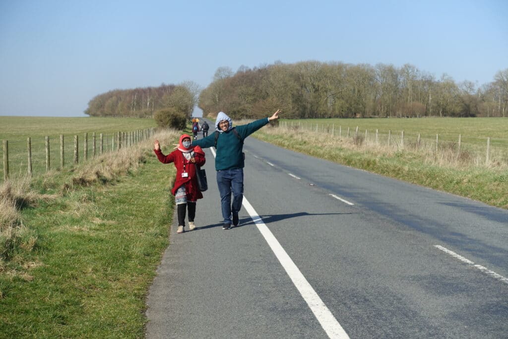 Two people holding their arms in the air walking along road.