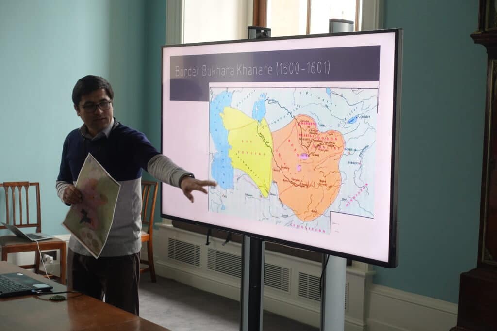 Uktamali points to a TV screen while giving a presentation