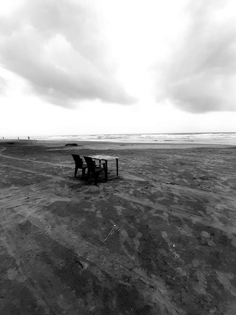 Two chairs and a table on a beach in Arambol, Goa, India.