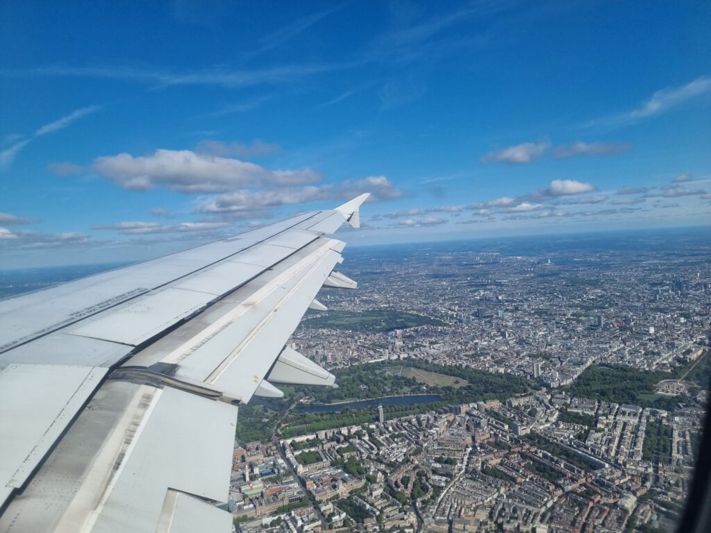 View from an aeroplane window with plane's wing in the foregroup and a view of a city below