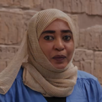 Asmahan Gabir, wearing a light coloured headscarf and blue top