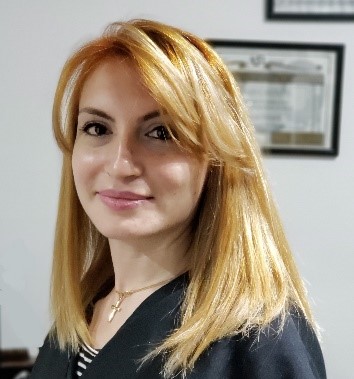 Tatevik Saroyan, wearing a black top standing in front of a white background.
