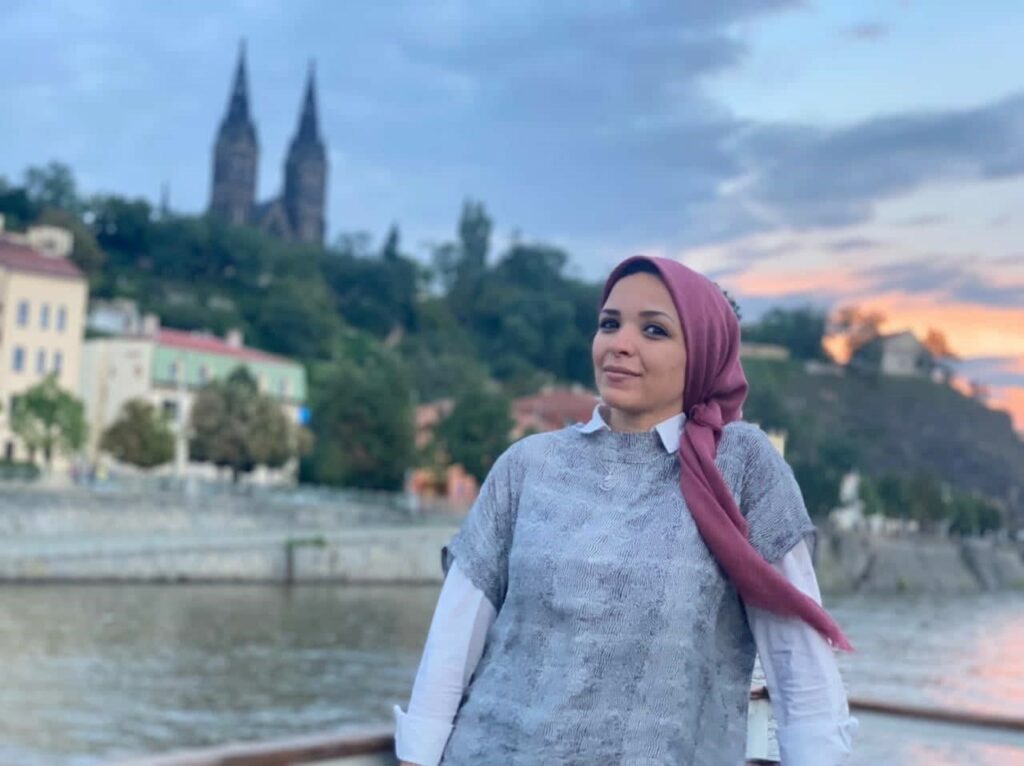 Noor standing in front of the Vltava river. 