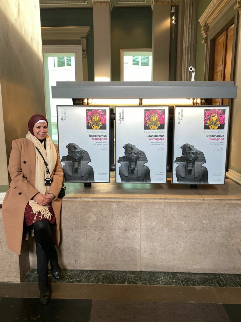 Heba Khairy standing next to posters for Tutankhamun Reimagined display