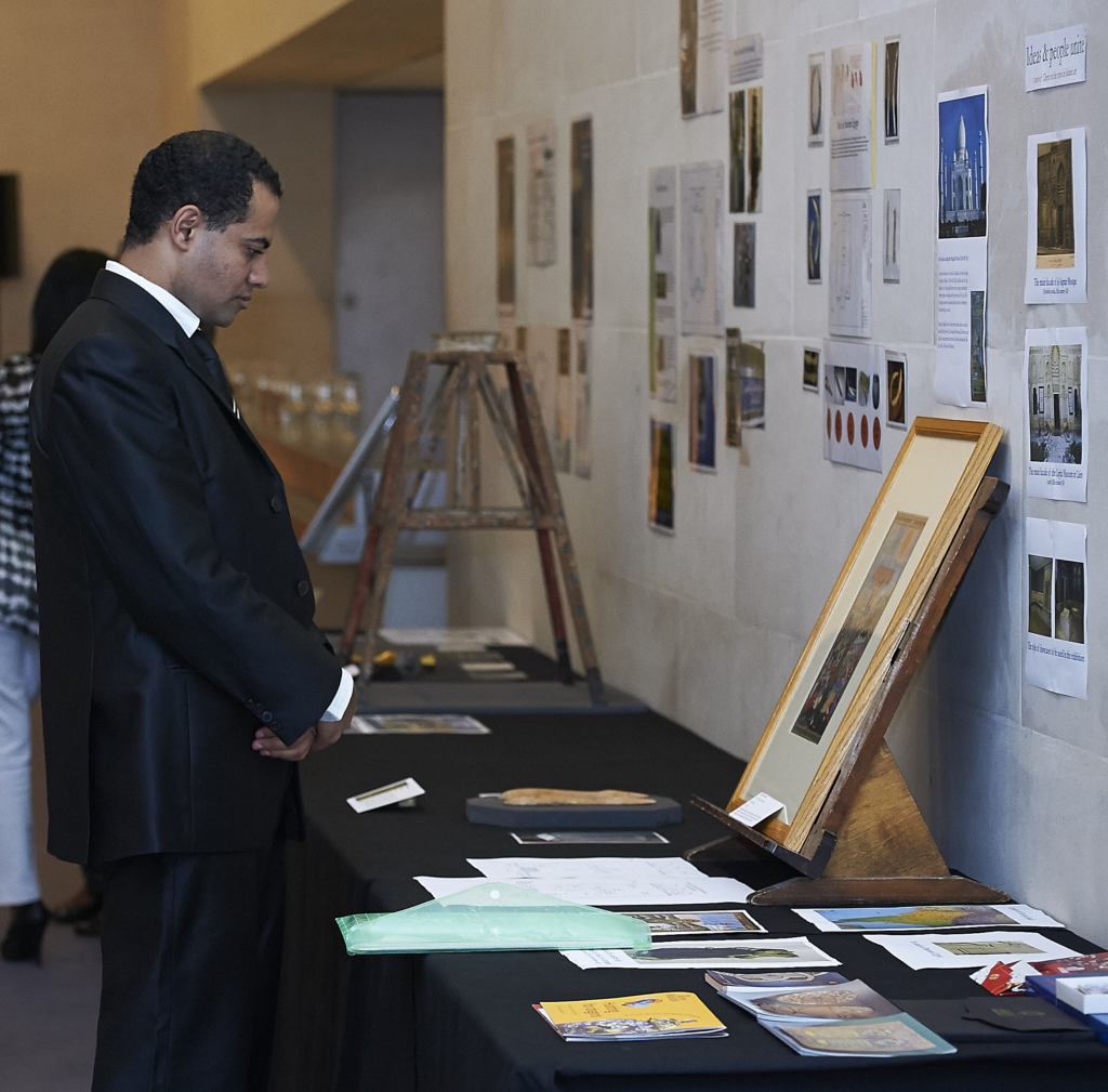 Mohamed standing in front of a table displaying an exhibition proposal