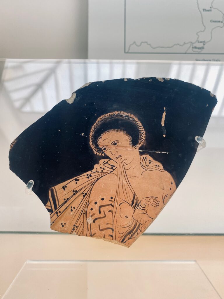 A fragment of a red-figured calyx-krater depicting a woman in Phrygian costume suckling an infant