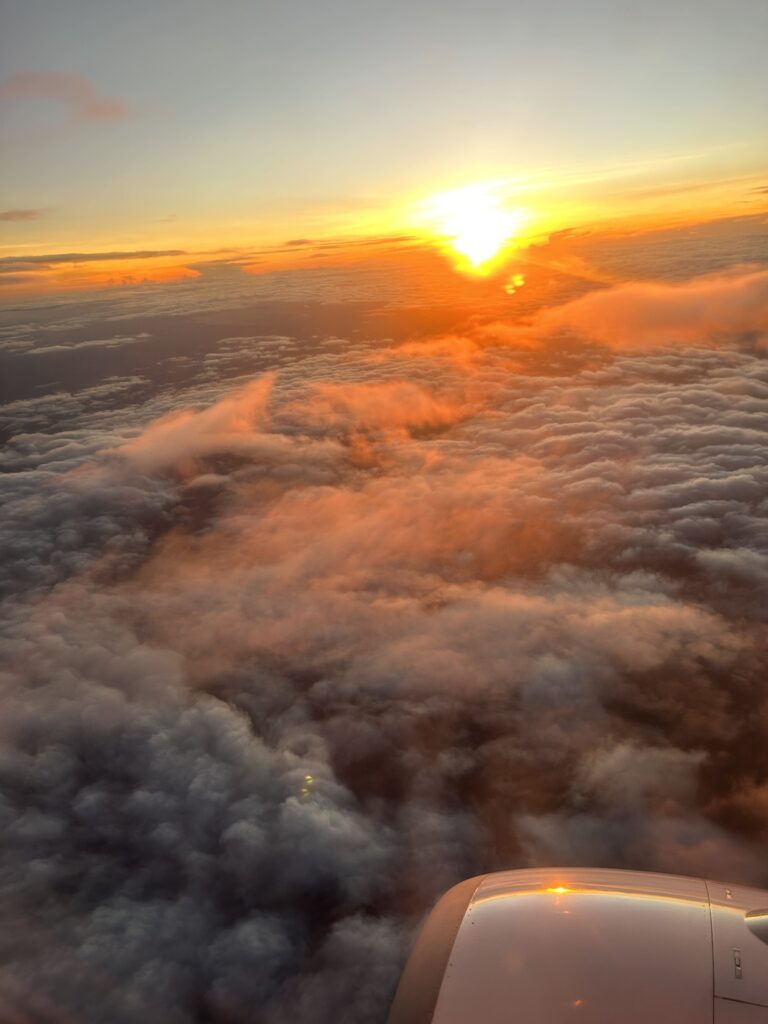 View of sunrise over clouds from a plane window.