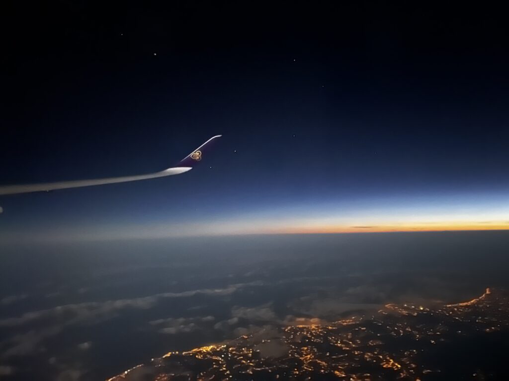 View of a plane wing from plane window at sunset.