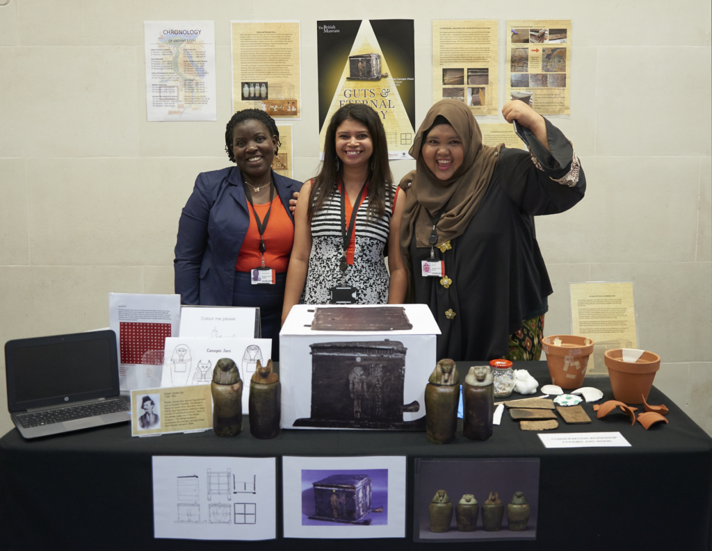 Three ITP fellows stand behind a table with their Object in focus project material on display