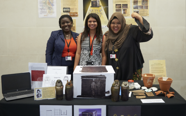 Three ITP fellows stand behind a table with their Object in focus project material on display