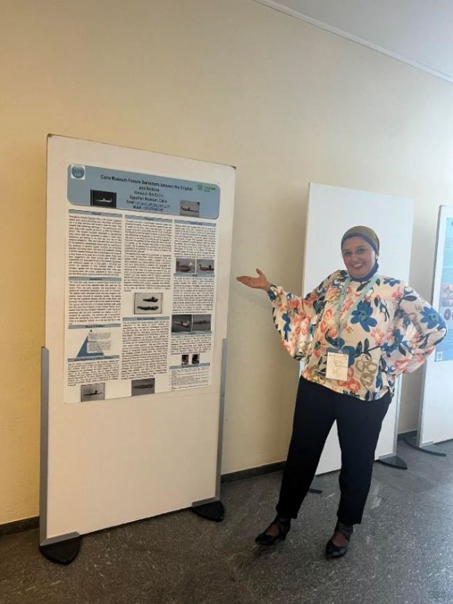 Marwa standing next to a board displaying her research.