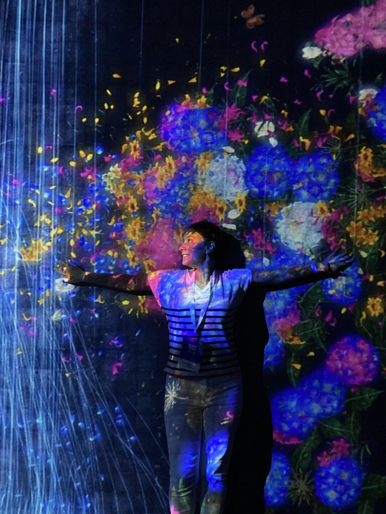 Rema standing in front of a brightly coloured projection at the Art Science Museum in Singapore.