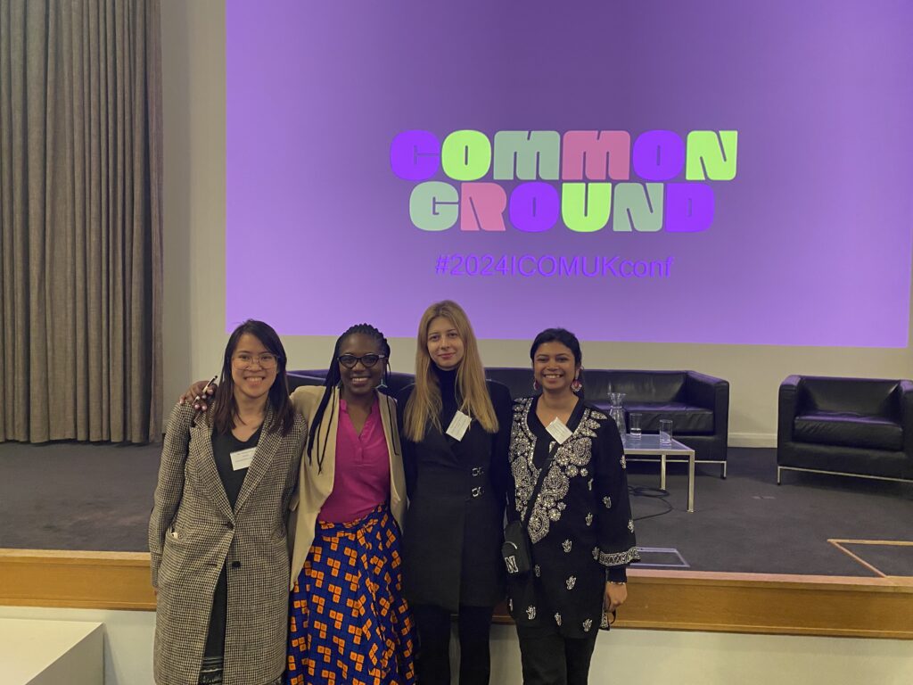 A photograph of four women standing in front of a projection that says 'common ground'