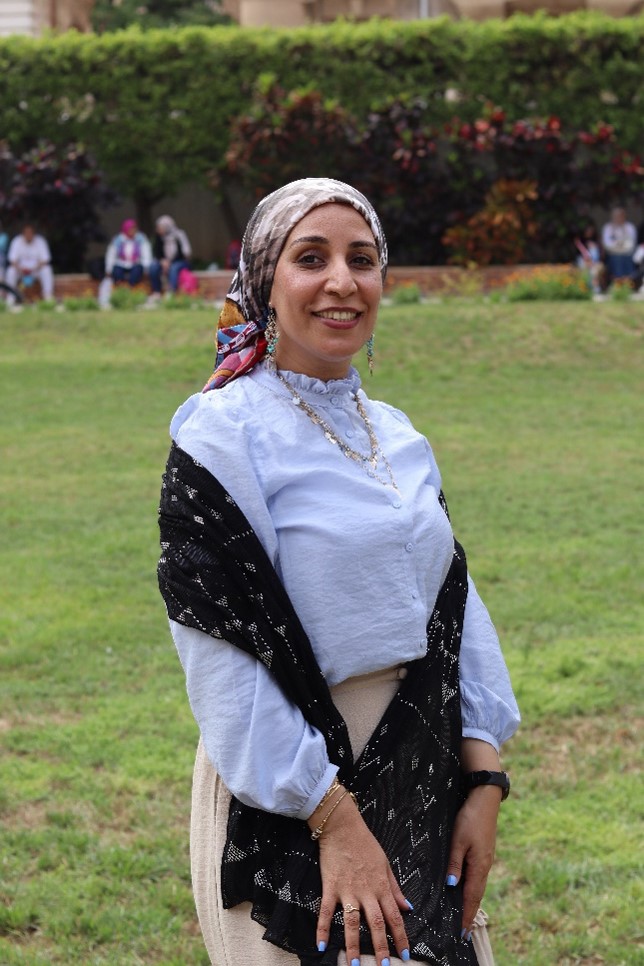 Photograph of a woman standing in a garden and smiling.