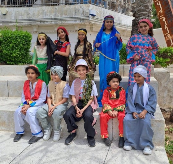 A photograph of 10 children stood wearing different traditional regional Egyptian dress.