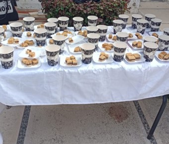 A photograph of a table covered in cups and plates with baked goods.