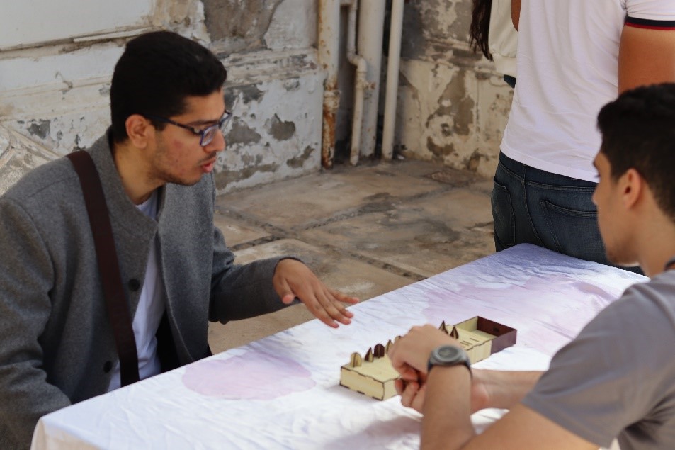 Two men sit opposite each other at a table playing the senet game.