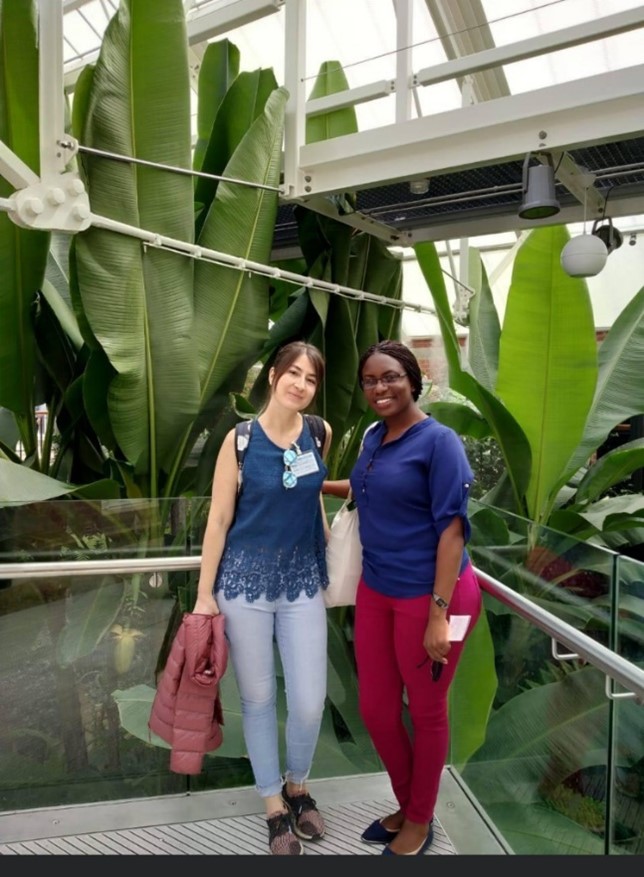 Two women stood on a platform in front of huge plants.
