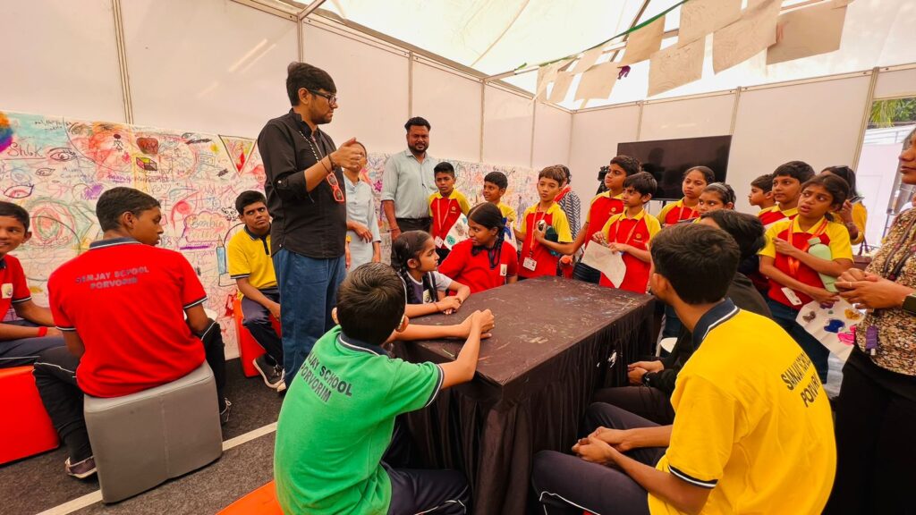 A man stood in front of children sat at tables.