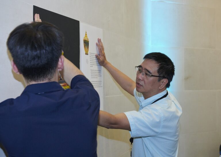 Photograph of two men putting a poster on a wall