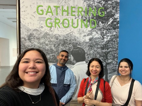 Four people taking a selfie in front of a sign saying Gathering Ground