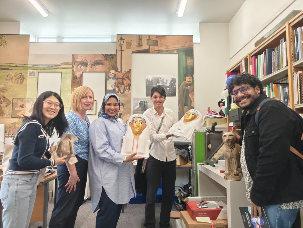 5 people posing for a photo with replica Egyptian artifacts