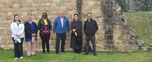 Photograph of six people in front of a wall