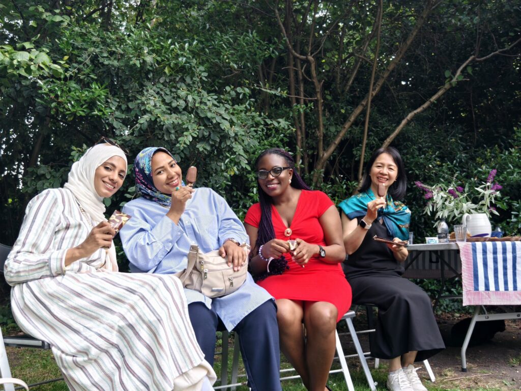 ITP fellows sitting in a garden holding ice creams and smiling for the camera
